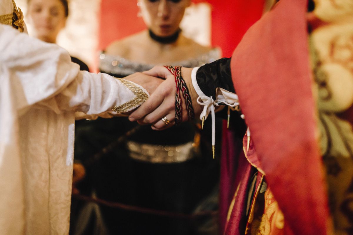 Il rituale dell'handfasting (mani degli sposi legate da una benda) durante il matrimonio medievale di Roberta e Alessandro