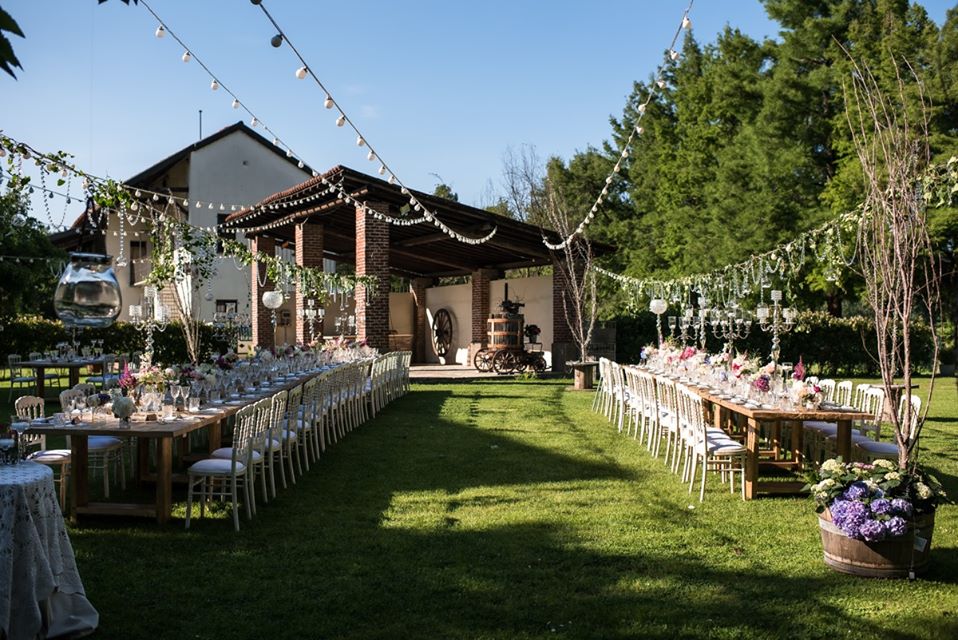 In questa foto gli spazi esterni di Cascina Boscaccio, alle porte di Milano, allestiti con decorazioni aeree e tavoli imperiali per un matrimonio dallo stile Country Chic