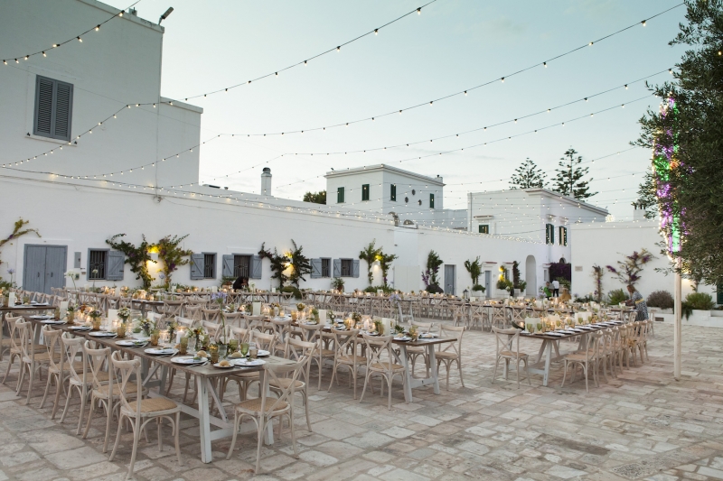 In questa foto, lunghi tavoli imperiali allestiti per un matrimonio negli spazi esterni di Masseria San Nicola, a Savelletri, in Puglia