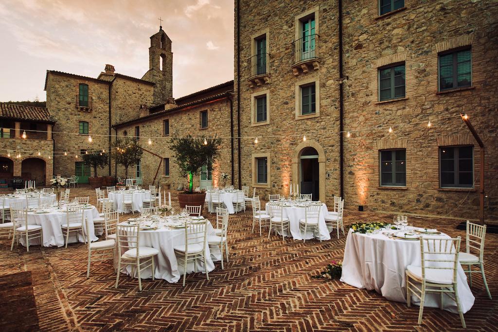 In questa foto la terrazza di Spao Borgo San Pietro, in Umbria, allestita per un matrimonio con tavoli rotondi e fili di luci sospese in cielo