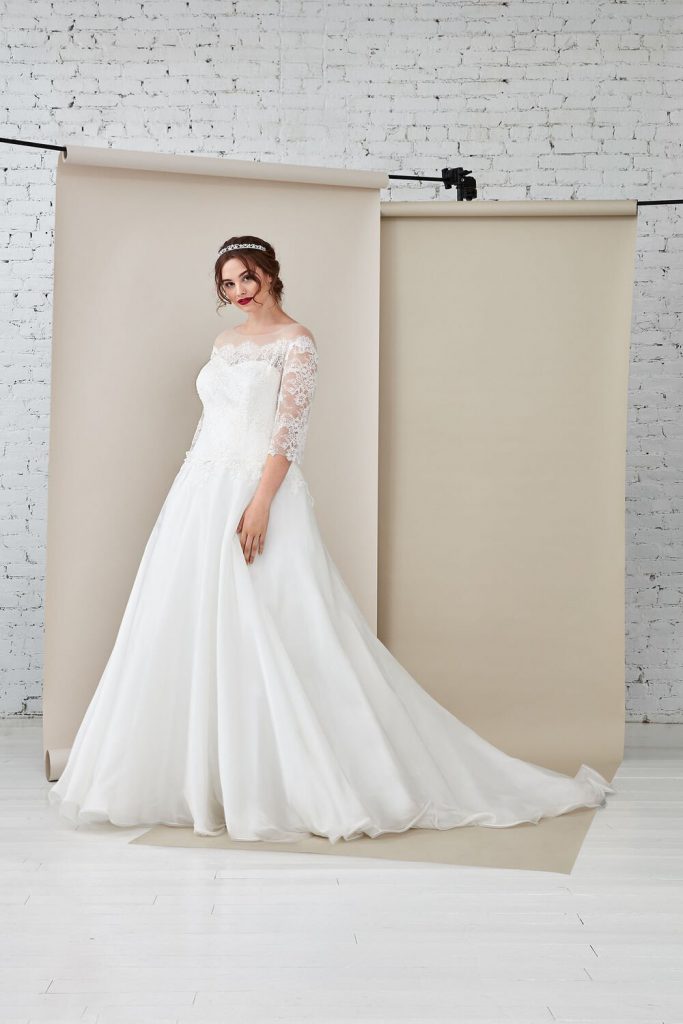 In questa foto un modello con maniche in pizzo proposto tra gli abiti da sposa curvy Atelier Emé