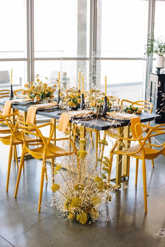 In questa foto un tavolo grigio senza tovaglia circondato da sedie e centrotavola gialli