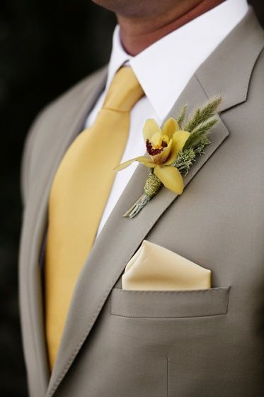 In questa foto fiore all'occhiello, cravatta e fazzoletto da taschino gialli per lo sposo che indossa un abito grigio