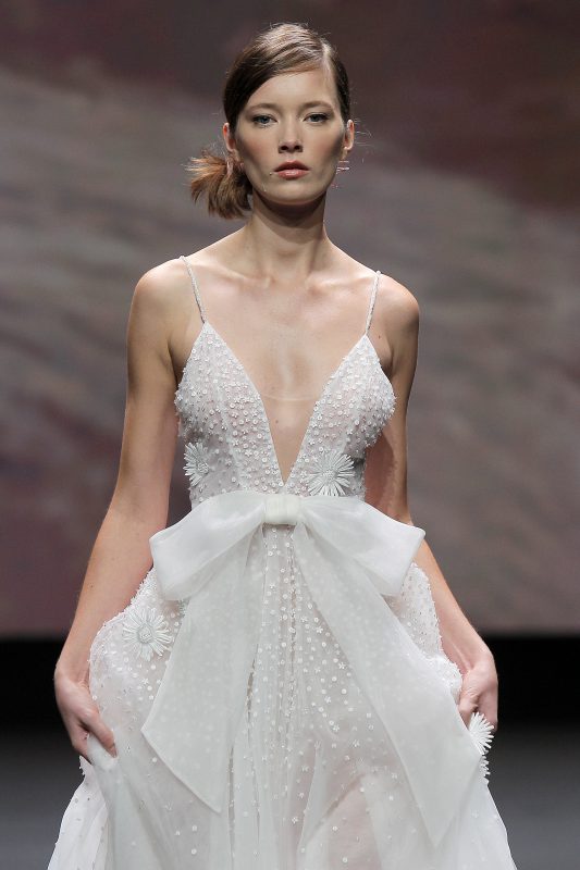 In questa foto un abito da sposa di Leonie Bridal con scollo a V e maxi fiocco