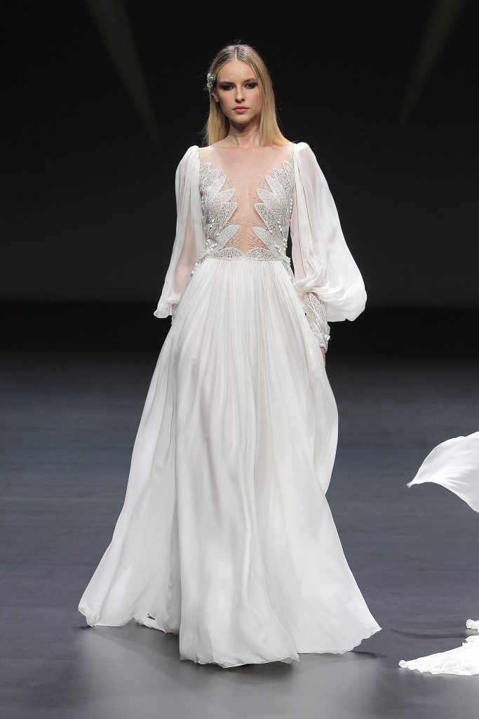 In questa foto una modella indossa un abito da sposa Pronovias con leggere maniche a palloncino durante la sfilata alla VBBFW20