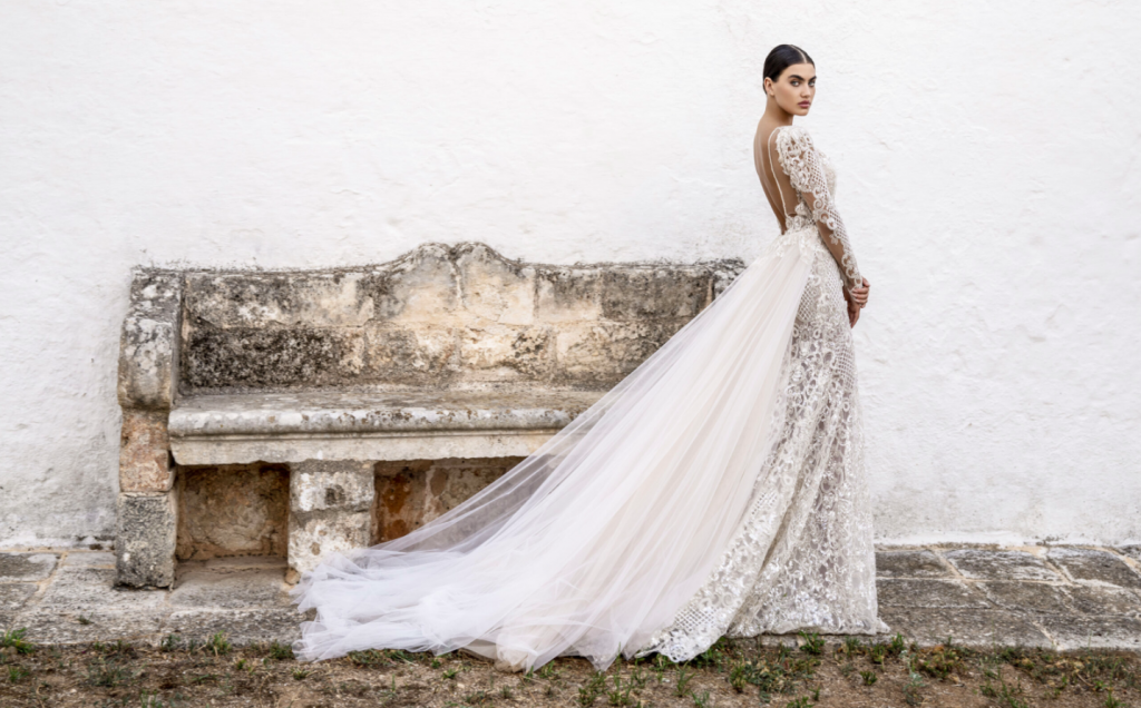 In questa foto una modella indossa un abito da sposa in pizzo, con sovragonna in tulle, firmato Alessandro Angelozzi Couture 2021