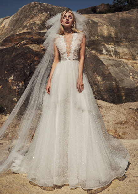 In questa foto una modella con addosso un abito da sposa in plumetis firmato Annylin Bridal 2021