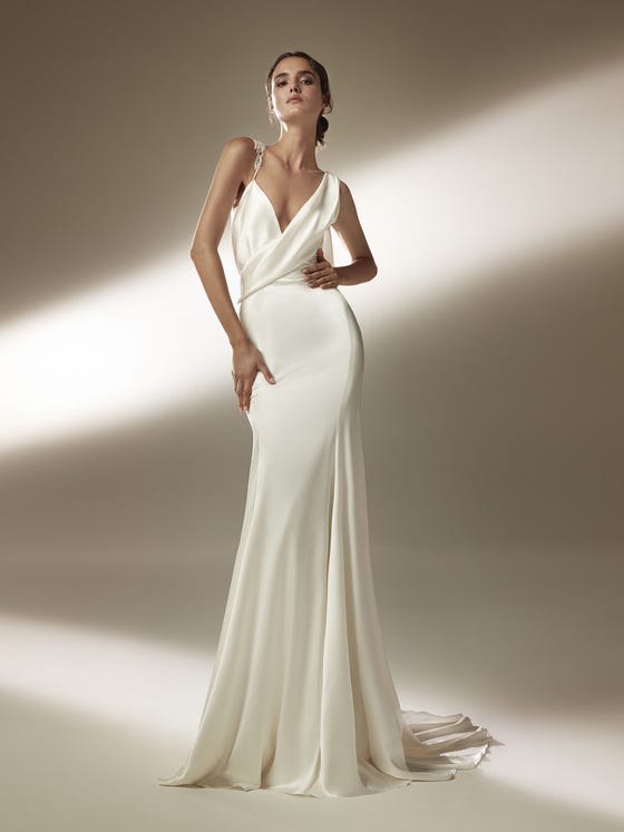 In questa foto una modella in posa con un abito da sposa a sirena di Atelier Pronovias 2021