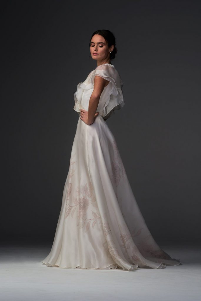 In questa foto una modella con un abito da sposa con delicati fiori dipinti a mano della collezione Chiara Vitale per Atelier Kore