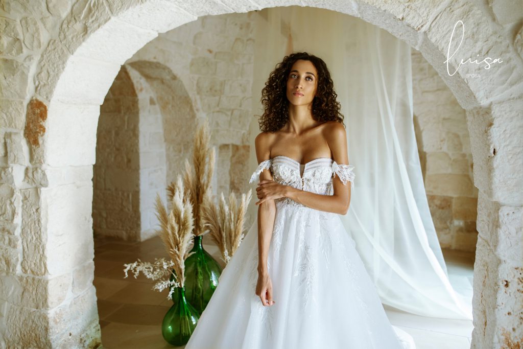 In questa foto una modella indossa un abito da sposa della collezione Luisa Sposa 2021