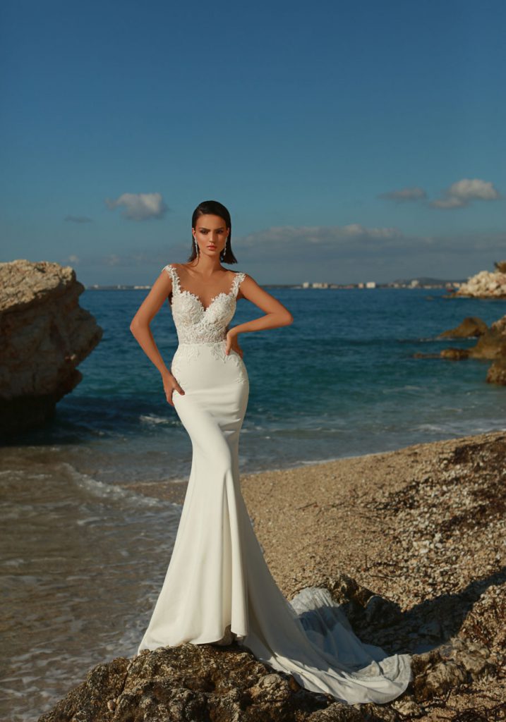 In questa foto una modella in riva al mare indossa un abito da sposa della linea Excellence di Maison Signore 2021
