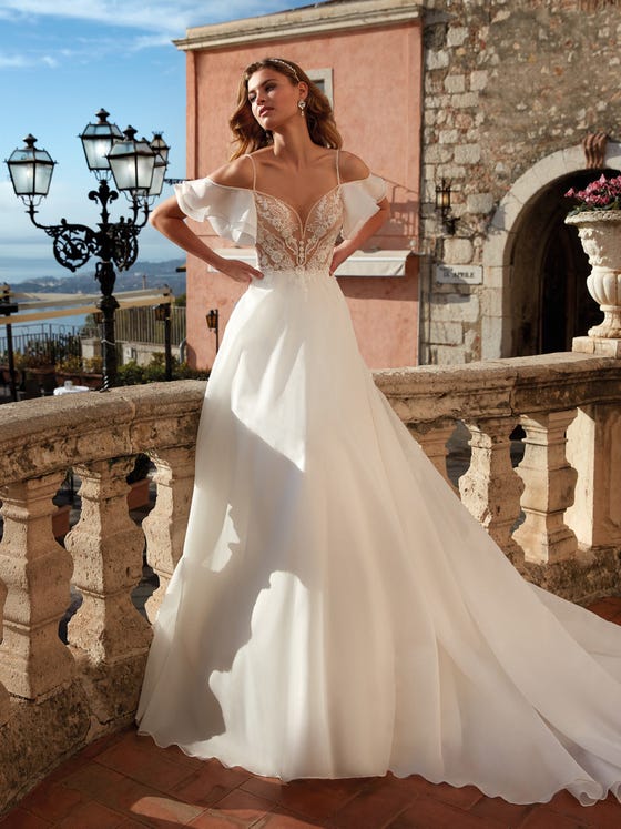 In questa foto una modella indossa un abito da sposa dalla linea scivolata della collezione Nicole Milano 2021