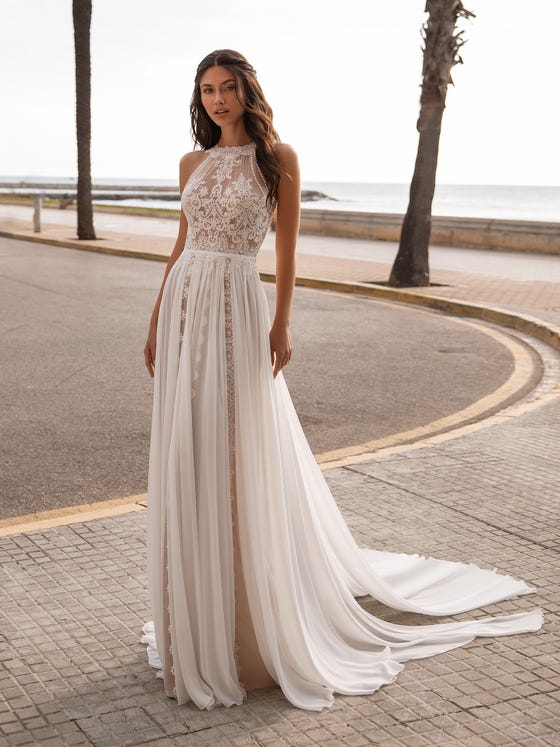 In questa foto una modella indossa un abito da sposa boho chic della collezione Pronovias 2021