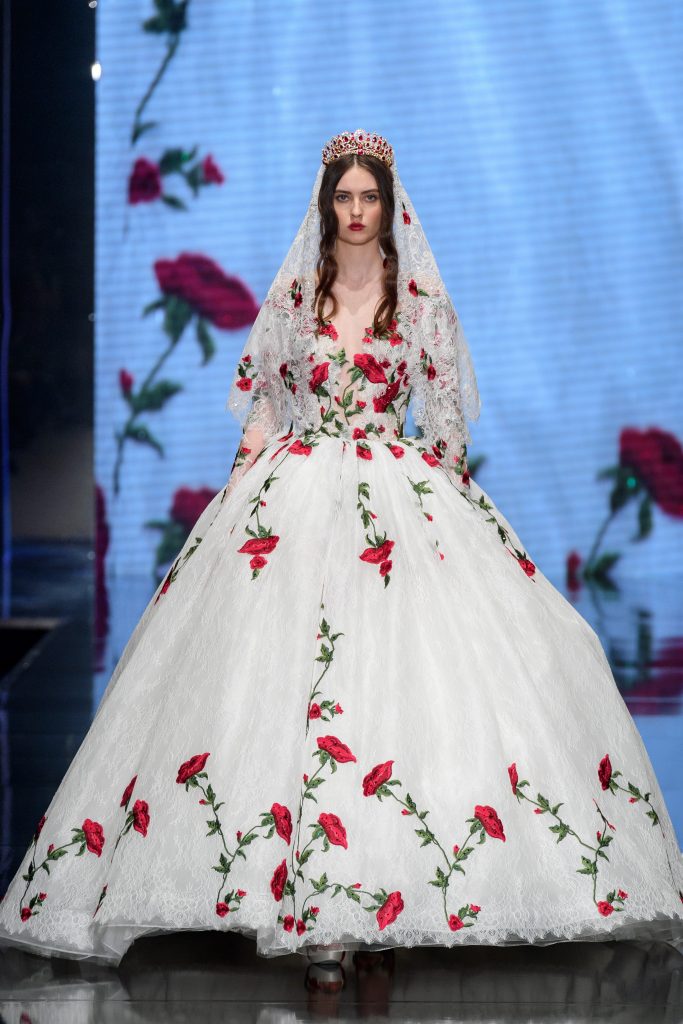 In questa foto una modella indossa un abito da sposa principesco con ricami di rose rosse firmato da Amelia Casablanca