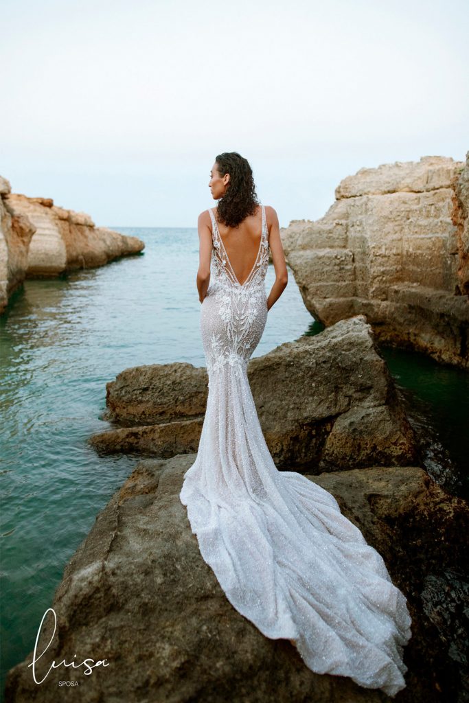 In questa foto una modella indossa un abito da sposa con scollatura a V sulla schiena della collezione Luisa Sposa