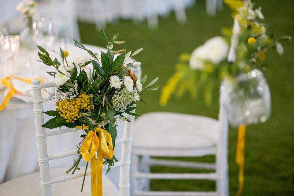 In questa foto un allestimento floreale su sedie Tiffany in bianco e giallo