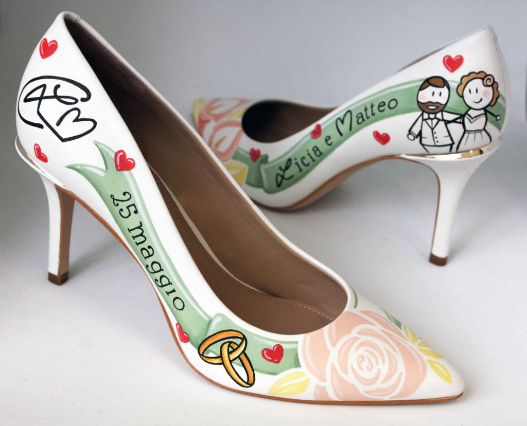 In questa foto un paio di scarpe da sposa personalizzate con disegni e scritte che richiamano alla mente gli sposi e il giorno delle loro nozze