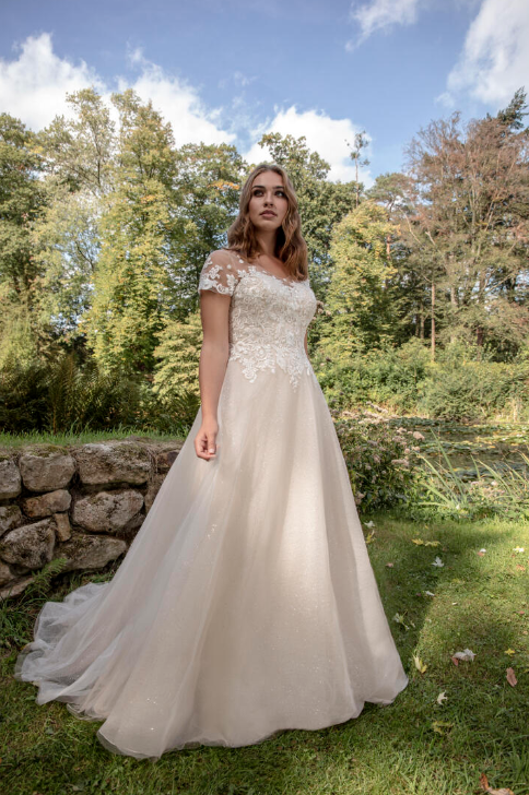 In questa foto una modella indossa un abito da sposa curvy di Le Papillon by Modeca