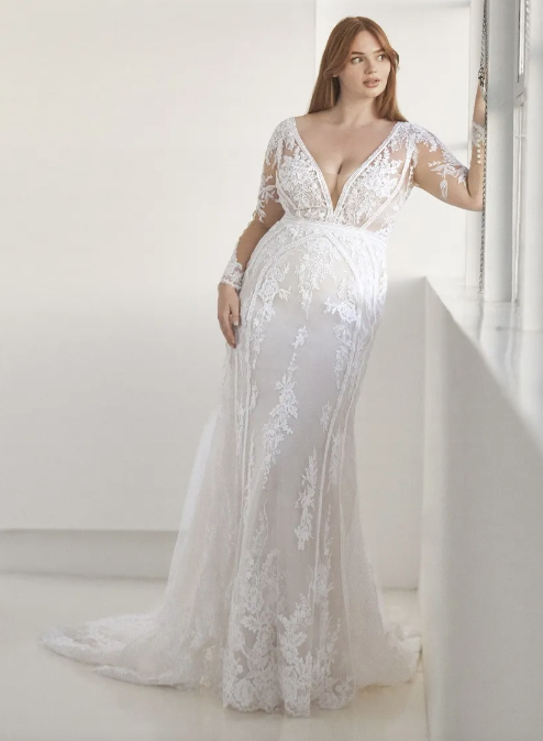 In questa foto una modella indossa un abito da sposa curvy firmato Pronovias