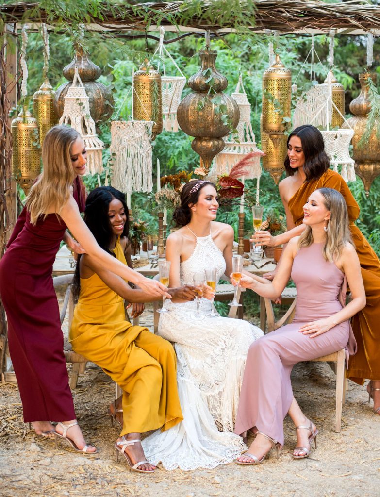 In questa foto le damigelle con la sposa indossano abiti perfetti per un matrimonio in stile Boho Chic: i colori sono ocra, arancione scuro, rosa antico e bordeaux