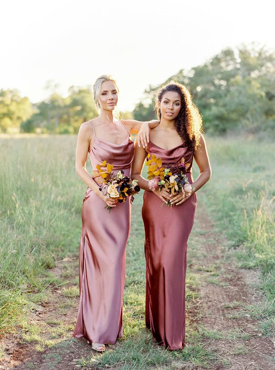 In questa foto due damigelle della sposa con abiti sottoveste in raso di seta nei toni del marsala chiaro e scuro