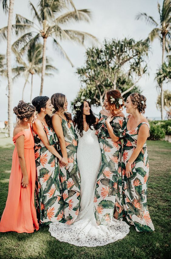 In questa foto una sposa con le sue damigelle vestite con abiti a fantasia tropicale. La damigella d'onore ha un abito diverso dalle altre, color pesco