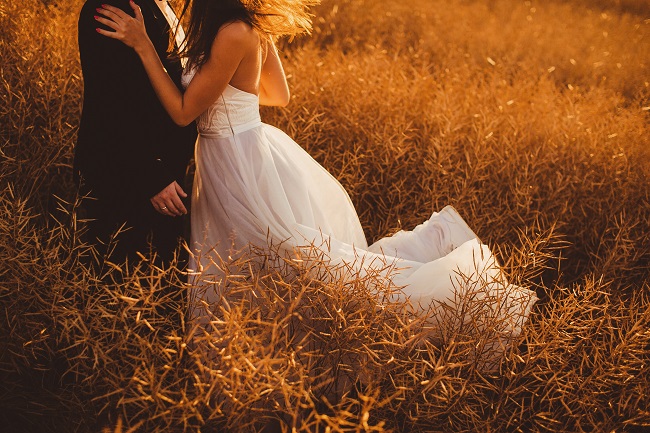 In questa foto una coppia di sposi mentre si abbraccia in un campo di fieno