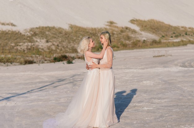 In questa foto due donne che hanno appena celebrato il loro matrimonio gay, mentre si abbracciano sulla spiaggia vestite da sposa