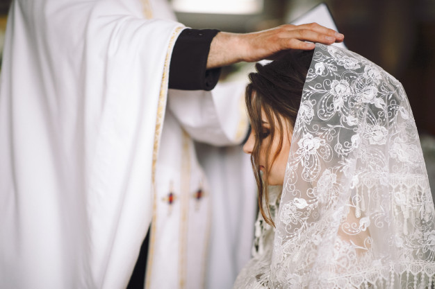 In questa foto un prete benedice una sposa durante la celebrazione di un matrimonio religioso