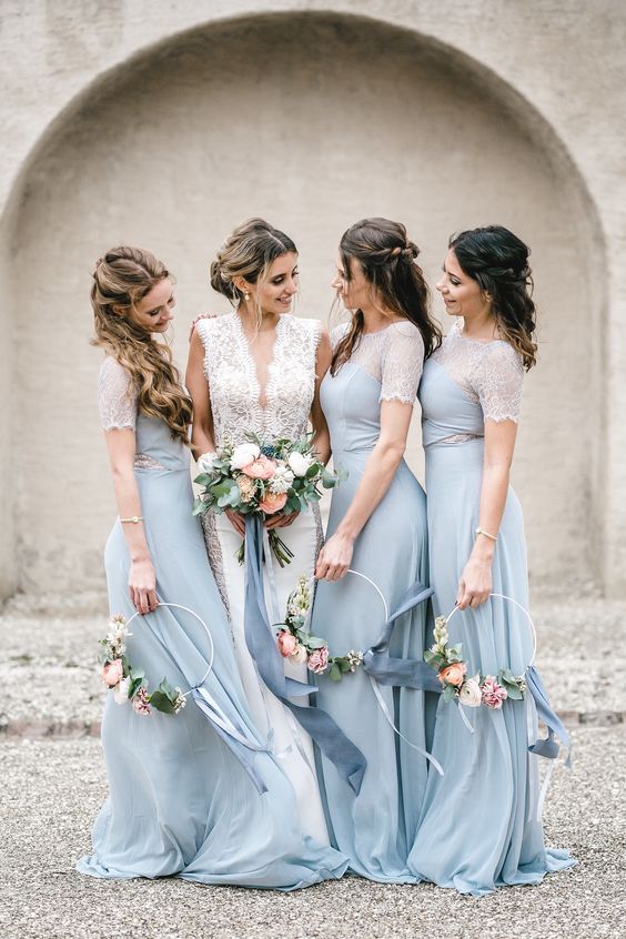 In questa foto una sposa con le sue tre damigelle vestite con abiti celesti, che tengono tra le mani i loro hoop bouquet