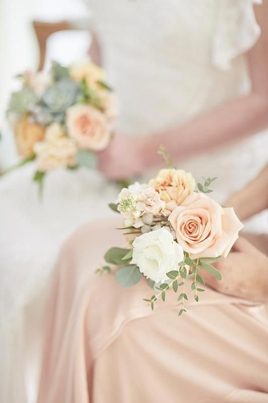 In questa foto una damigella tiene tra le mani il suo mini bouquet, più piccolo per dimensione ma uguale a quello della sposa accanto a lei