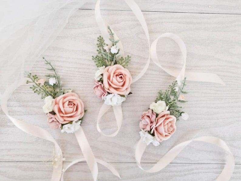 In questa foto tre corsage floreali realizzati con rose rosa e bianche e qualche ramoscello verde