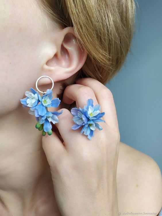 In questa foto una modella indossa un orecchino e un anello realizzati con gli stessi boccioli di fiori