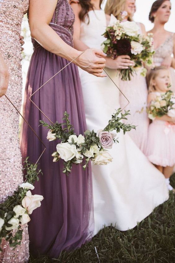 In questa foto una sposa e le sue damigelle grandi e piccine. Quelle adulte tengono tra le mani un hoop bouquet di forma romboidale