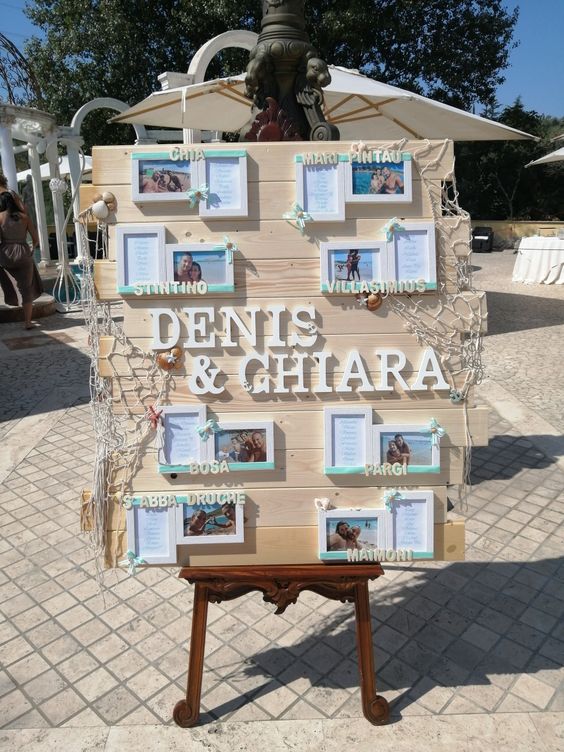 In questa foto un tableau mariage a tema mare realizzato con tegole di legno disposte in orizzontale a cui sono state applicati dei quadretti con le foto degli sposi in spiaggia e le liste degli ospiti divisi per tavolo