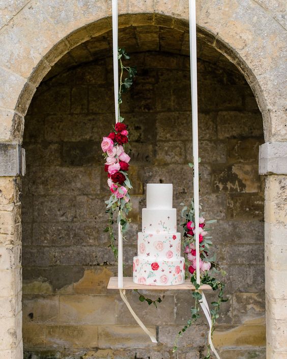 In questa foto una torta per matrimonio floreale su un'altalena