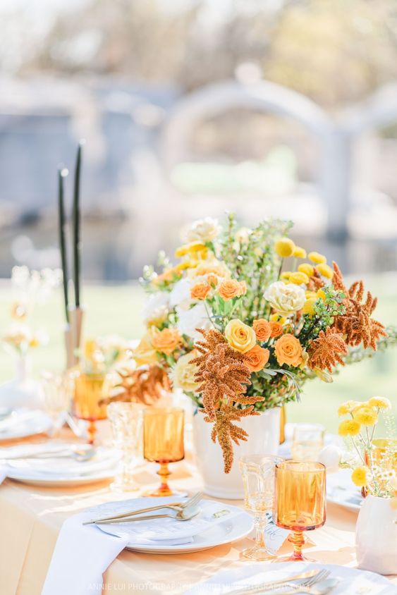 In questa foto una mise en place per un matrimonio a tema giallo e arancio, perfetta per nozze primaverili. Come centrotavola è presente un vaso di fiori di campo e tovagliato e bicchieri sono in pendant.