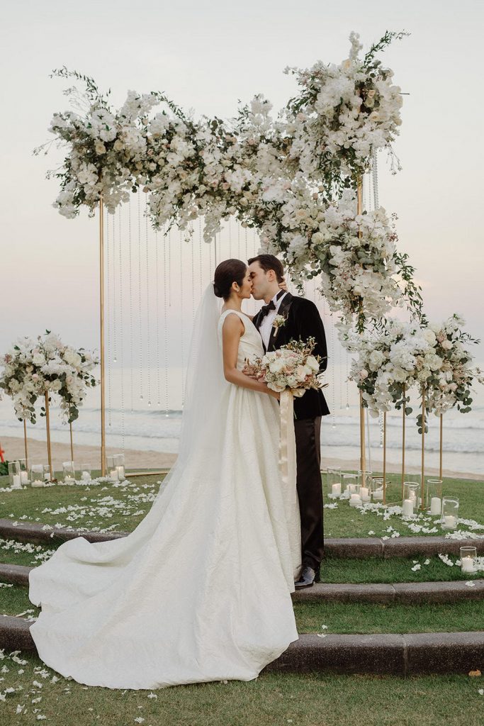 In questa foto due sposi che si baciano dopo la celebrazione del loro matrimonio all'aperto sul mare