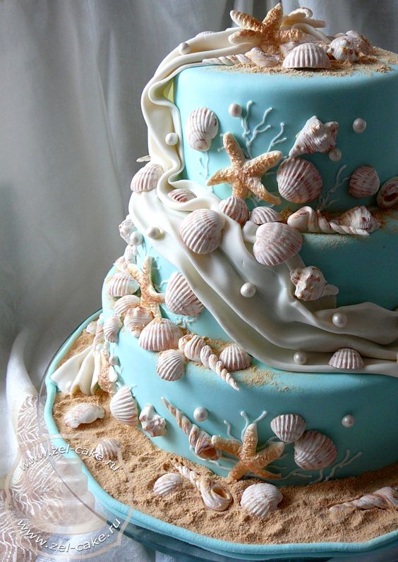 In questa foto una torta nuziale a tre piani con pasta di zucchero nel colore Tiffany decorata con tante conchiglie e stelle marine