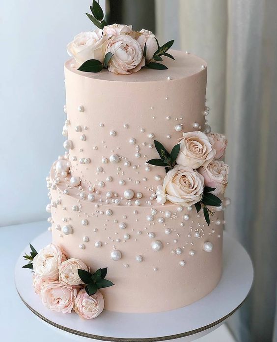 In questa foto una torta nuziale rosa decorata con perle edibili e rose vere