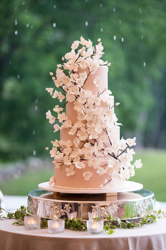 In questa foto una torta per matrimonio a 4 piani rosa con i rami e i fiori di ciliegio come decorazioni 3D 