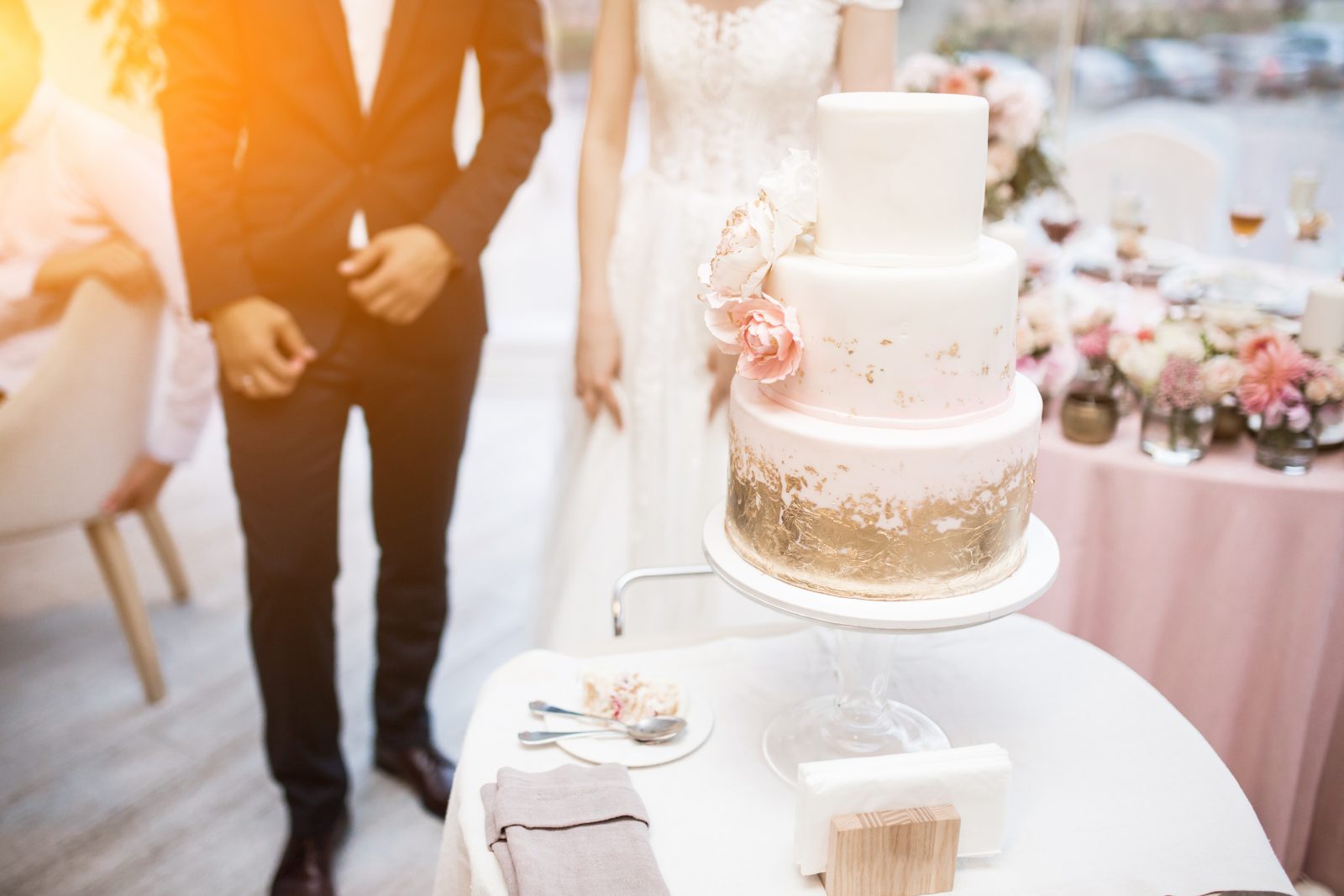 In questa foto una coppia di sposi davanti alla loro torta per matrimonio