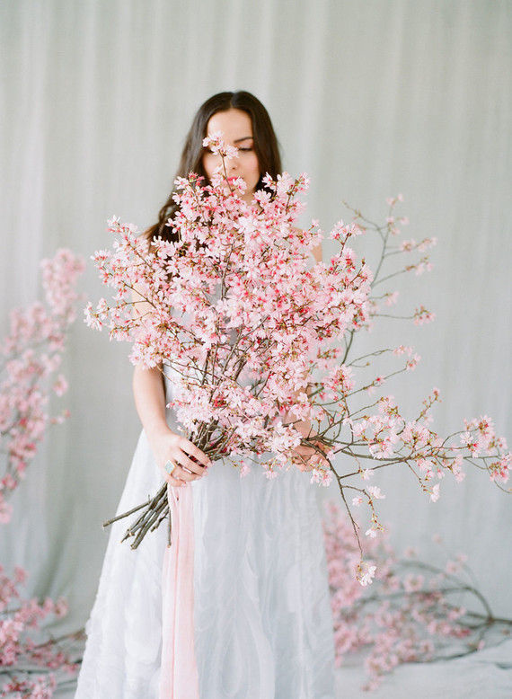 In questa foto un bouquet da sposa a braccio con rami di ciliegio 