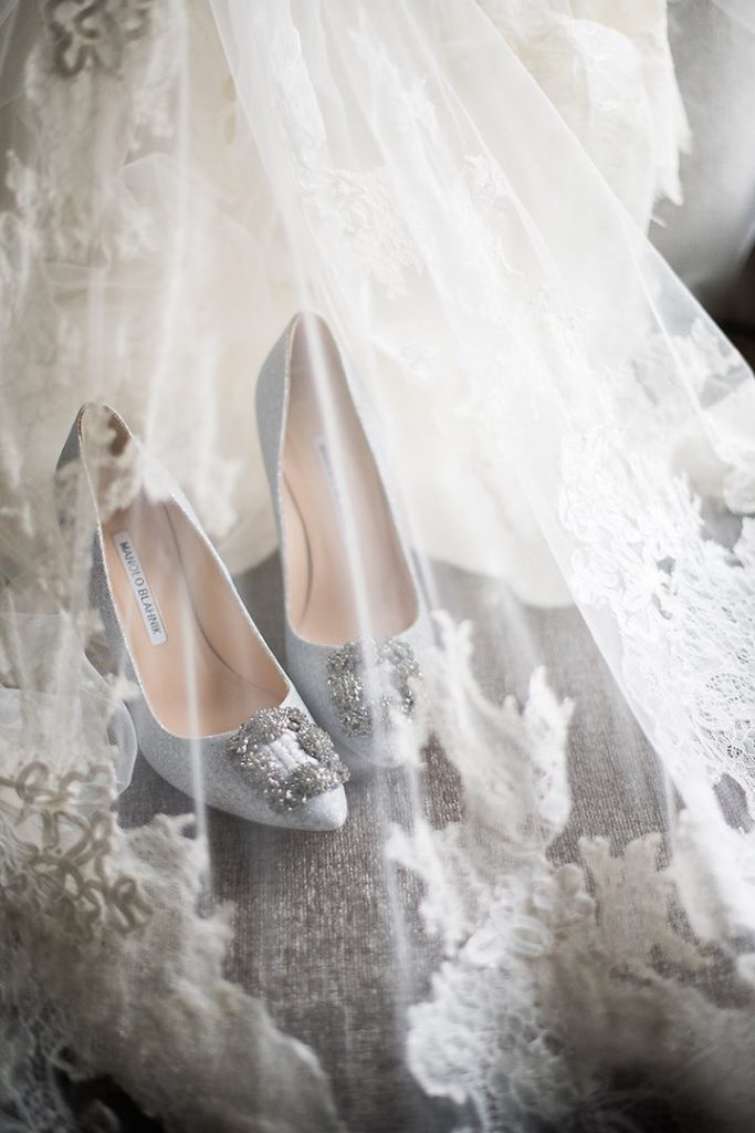 In questa foto un paio di scarpe da sposa Manolo Blanhik fotografate sotto un belo decorato con pizzo chantilly