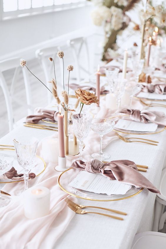 In questa foto una mise en place per un matrimonio elegante e romantico con tovaglia bianca e tovaglioli rosa antico e candele ecrù