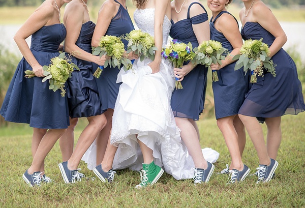 In questa foto una sposa con  Converse verdi posa con le sue sei damigelle vestite di blu scuro e Converse in coordinato. Tra le mani tengono tutte un bouquet di fiori verdi e blu