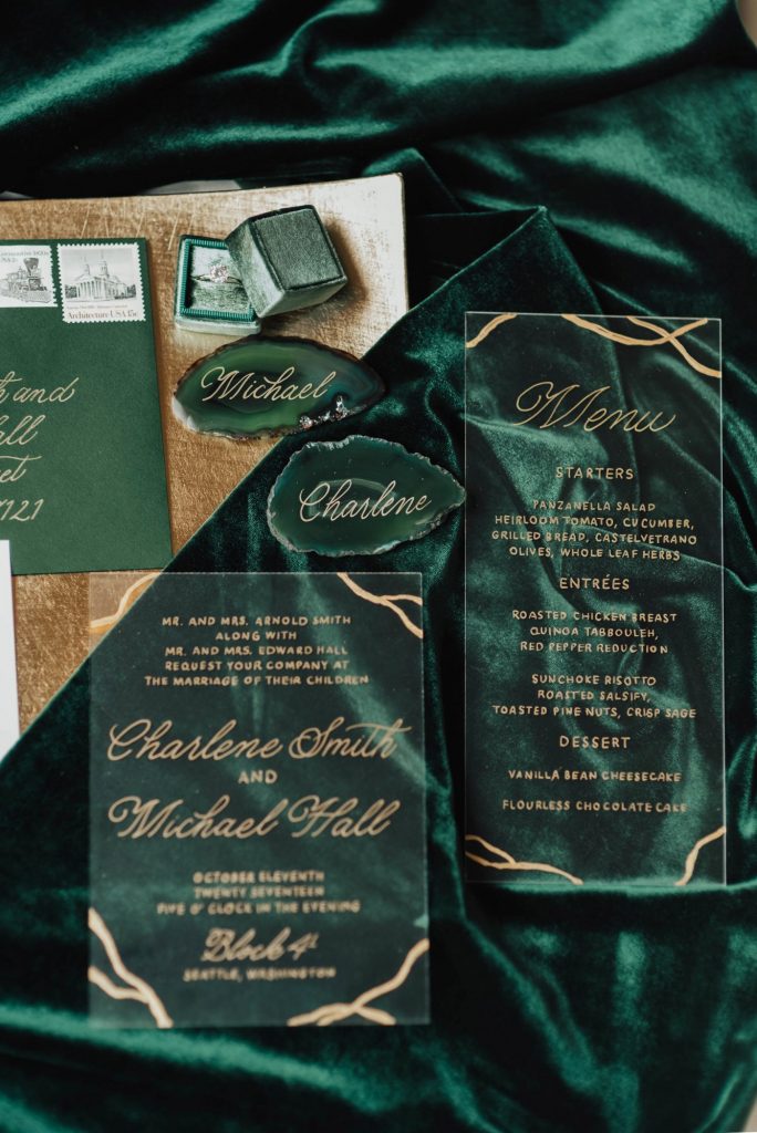 In questa foto una wedding stationery, cioè il coordinato cartaceo di un matrimonio, colore smeraldo. La partecipazione e il menù sono stampati su carta plastificata e trasparente con caratteri e decorazioni oro