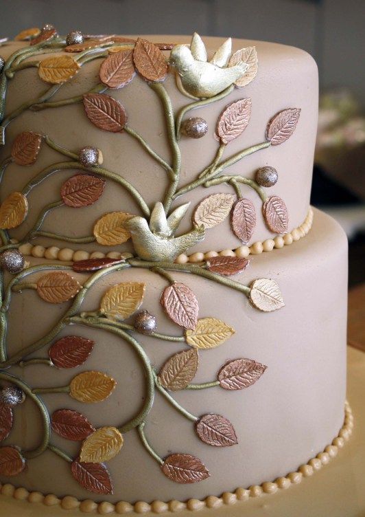 In questa foto una torta nuziale a tema albero della vita nel colore cipria. È decorata con rami e foglioline di pasta di zucchero nei colori oro e bronzo