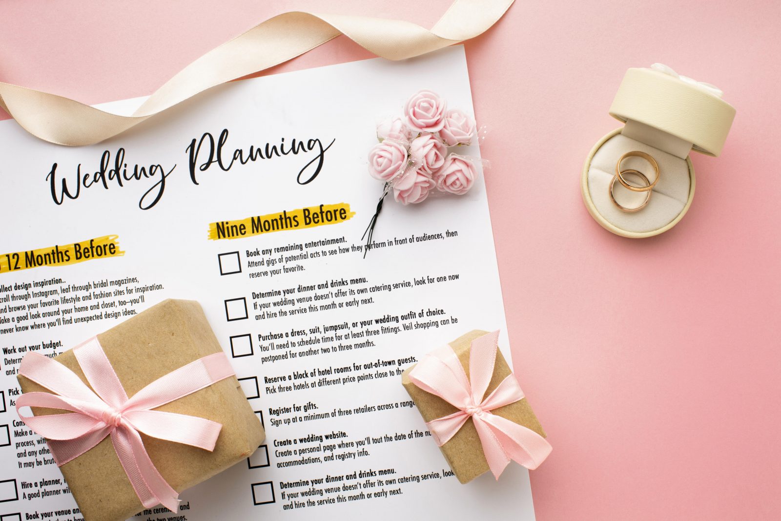 In questa foto il calendario di un wedding planner su sfondo rosa e piccole scatole in cartoncino