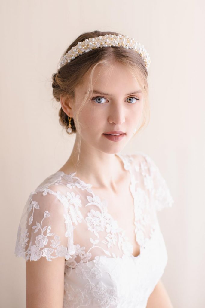In questa foto una modella indossa un cerchietto da sposa interamente ricoperto di perline gialle e bianche